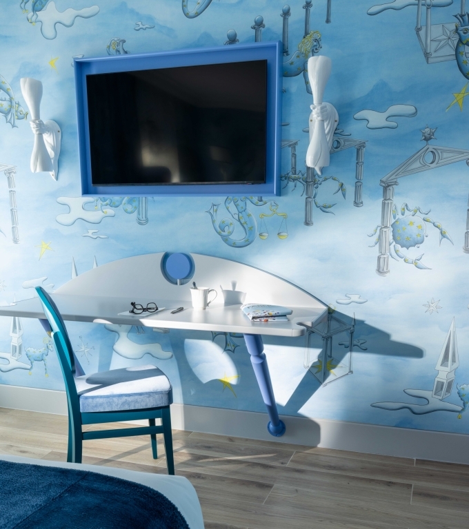 Curtains featuring artistic blue prints and elegant decor, the "D&eacute;couverte" room at the H&ocirc;tel Le Magnifique Paris